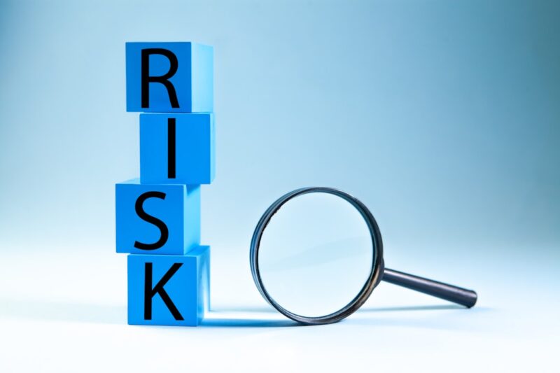 Business and finance concept. Word RISK on blue cubes with magnifying glass